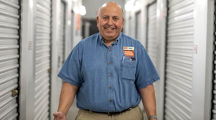 public storage employee smiles while standing in the middle of the hallway